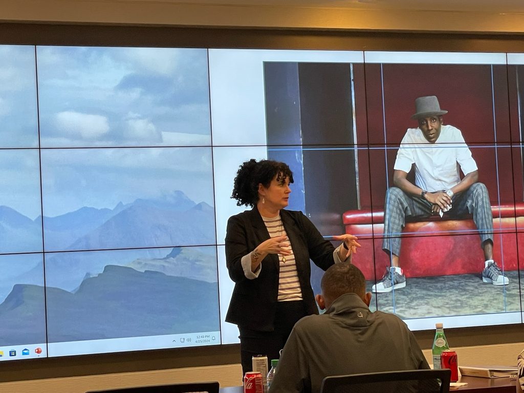 Heather Worthan presenting to a group in a conference room with large screens