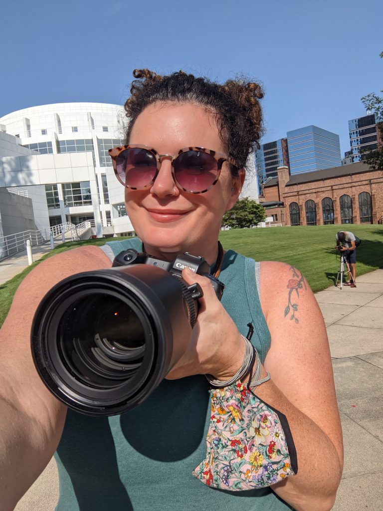 Heather Worthan holding a camera with the Atlanta skyline in the background